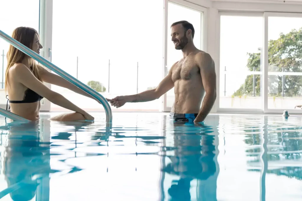 Uomo e donna si tengono mano in piscina.